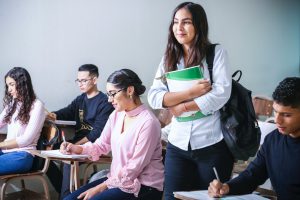 female holding book in classroom of peers